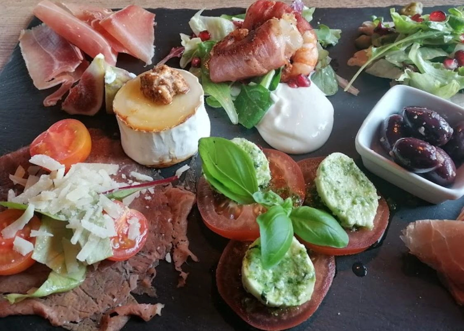 Neuling Weinbar – Gastronomie – Diese Platte enthält eine Auswahl italienischer Antipasti, darunter Wurstwaren wie Prosciutto und Bresaola.